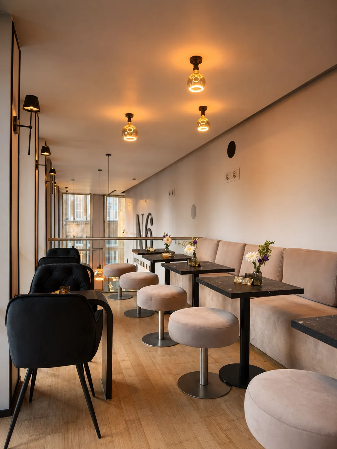 Loungebereich mit heller Polsterbank, Sitzhockern und Marmortischen auf der Galerieebene