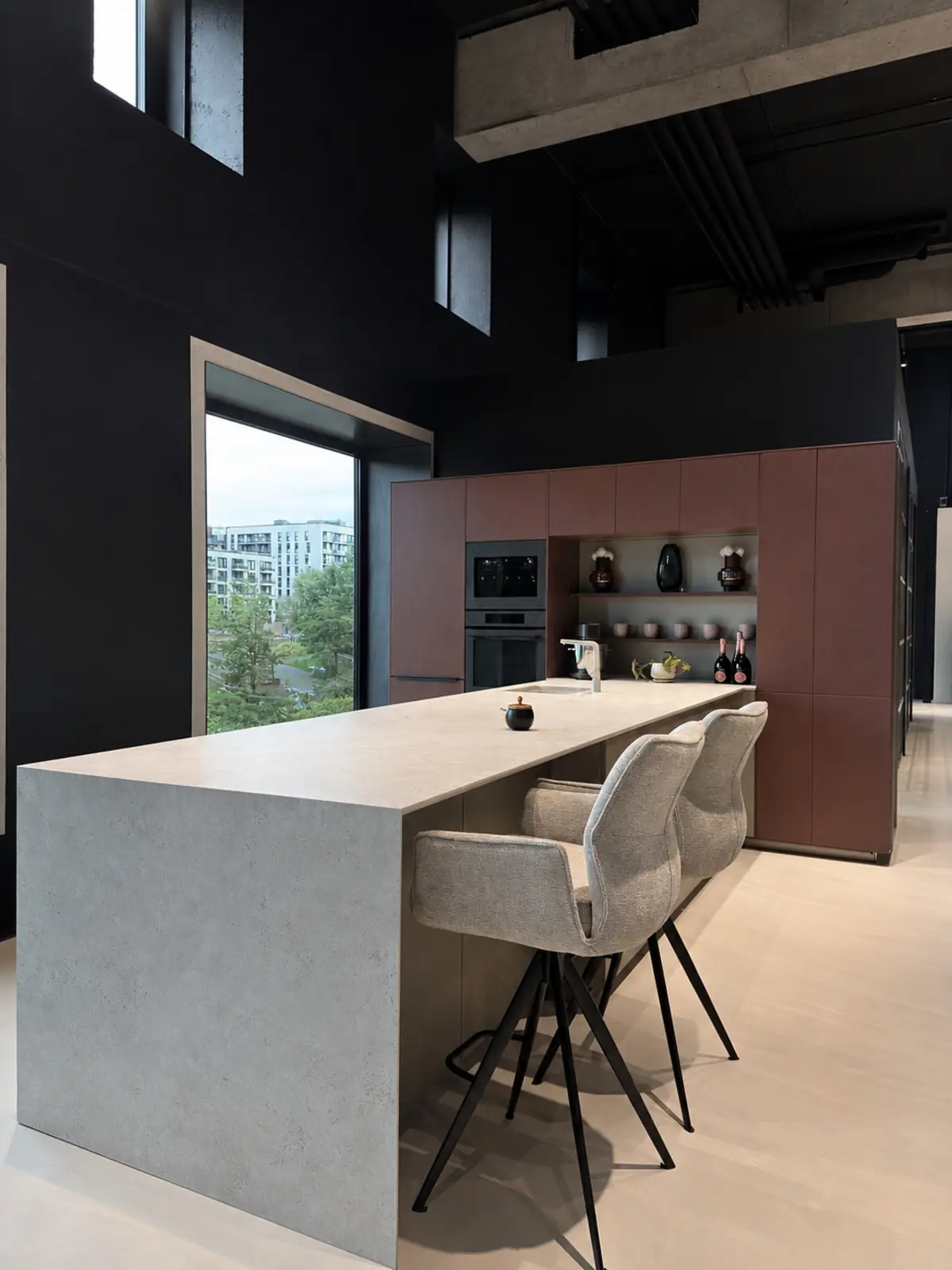 Freistehende Kücheninsel mit grüner Naturstein-Arbeitsplatte und dunklen Holzfronten im offenen Showroom der HafenCity